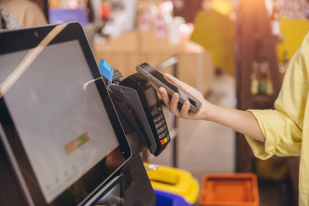 istock Customer using smartphone to pay at self checkout kiosk in supermarket 2230981938