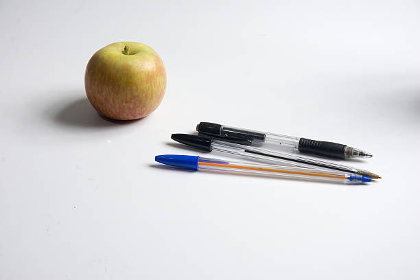 Pencils, pens and apple on a white background. Back to school.