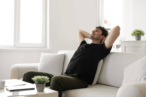 istock Smiling young male resting on sofa at home 2230984051