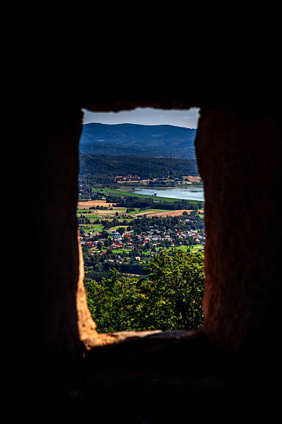 A view from a stone window opening frames a vibrant green landscape below.