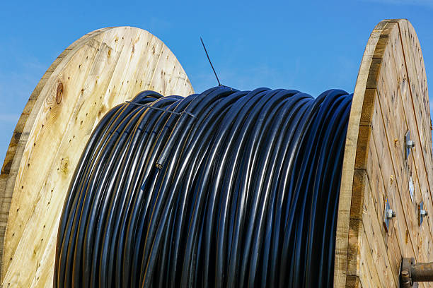 istock Large wooden spool with black utility cable for electrical or communication installation outdoors 2230987818