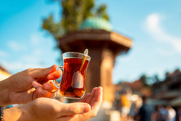 Man hands with a traditional Turkish tea (Çay) in a small, tulip-shaped glass called \