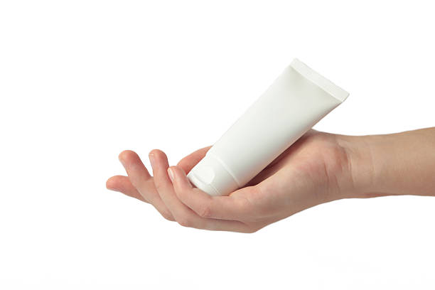 Hand holding blank white plastic tube isolated on white background. Cosmetic beauty product branding mockup.