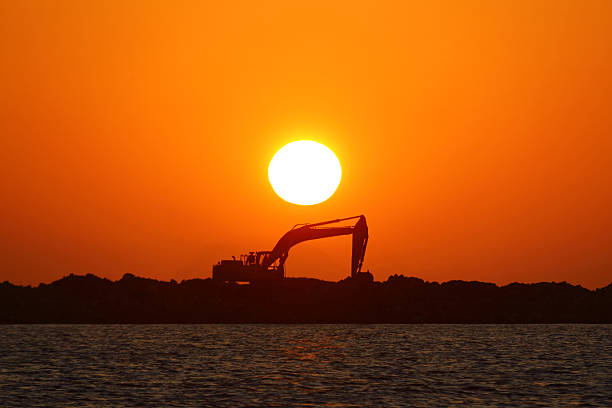 Excavator at a construction site against the setting sun.