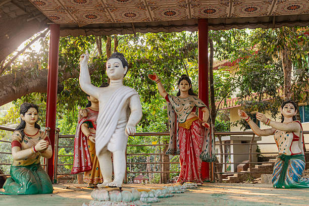 istock Majestic baby Buddha statue surrounded by graceful attendant figures under leafy temple tree background. 2231005538