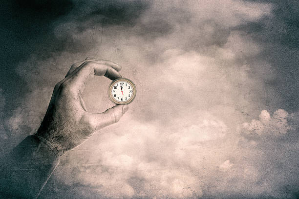 Hand holding clock over sky