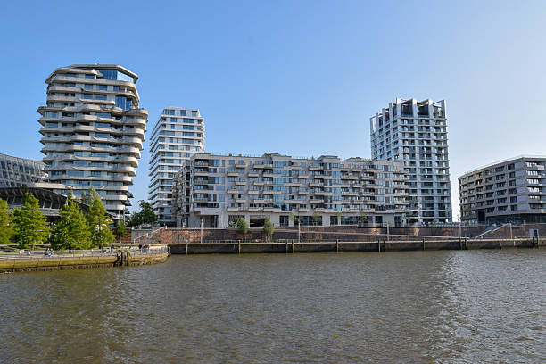 istock Modern waterfront buildings in Hamburg’s HafenCity rise under a clear blue sky, reflecting sunlight onto the Elbe River below 2231011068