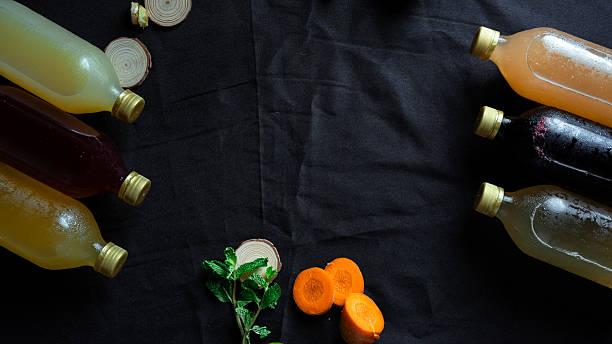 Variety of kombucha flavors on black background with ginger, carrot, and mint
