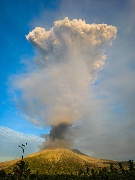 An awe-inspiring aerial photograph captures the majestic Mount Semeru volcano in East Java, near Surabaya, Indonesia, during a volcanic eruption, with smoke and ash plumes rising above the surrounding landscape of rice fields and rural villages.