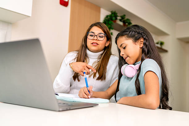 istock Mother helping daughter with schoolwork at home using laptop 2231016576