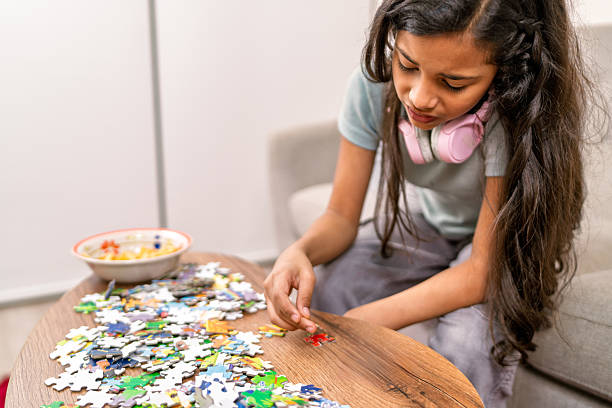 istock Girl concentrating on solving jigsaw puzzle at home 2231016593