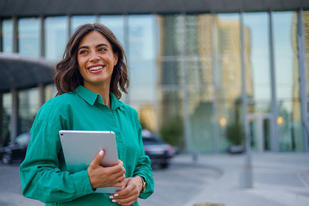 istock Professional woman networking, using digital tablet near contemporary glass office facade with cityscape background 2231019763
