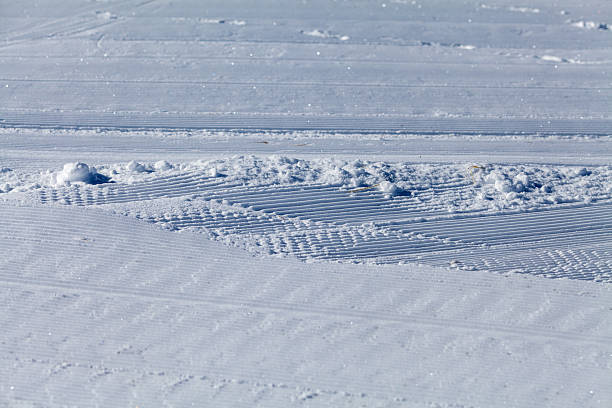 Close-up of a freshly groomed ski slope with parallel textured lines in the snow. Winter background concept for skiing, sports, and outdoor activities