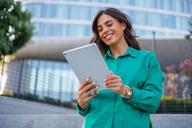 istock Young businesswoman holding a digital tablet and smiling while standing outside a modern office building 2231020712