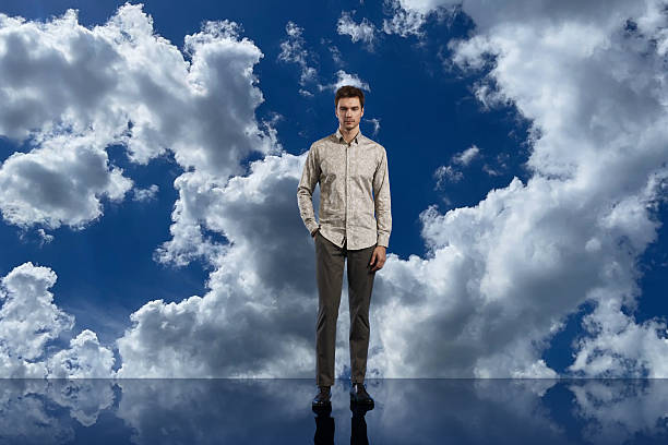 istock Stylish Man in Patterned Beige Shirt Against Blue Sky Clouds 2231022860