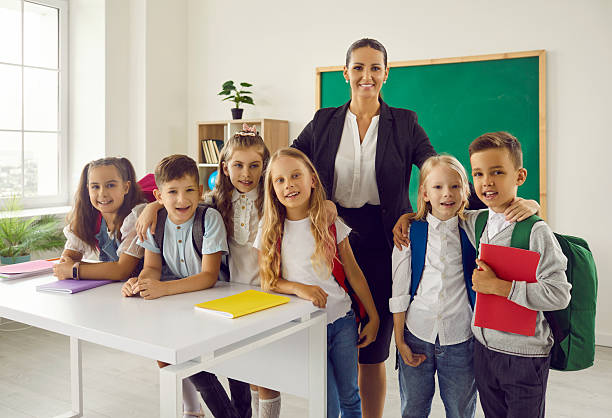 istock Portrait of elementary school teacher posing with students at camera 2231027464