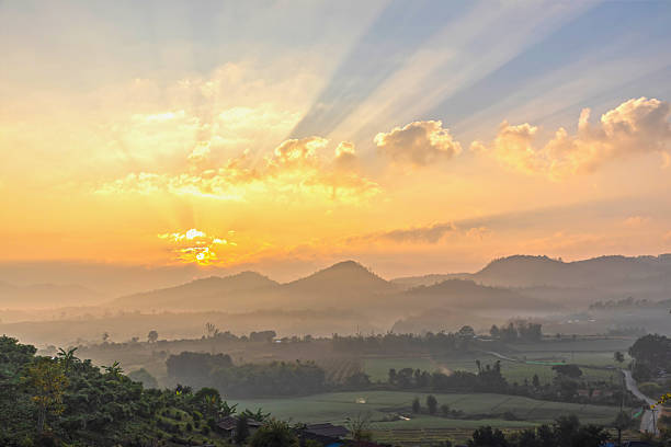 The morning sun shines through the fields surrounded by mountains.