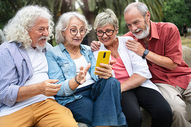 istock Group of modern senior friends using mobile phone app, laughing having fun sharing content on social media 2231039472