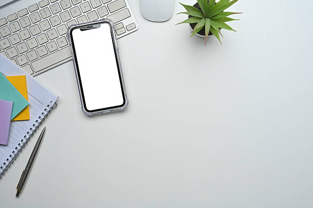 Workspace setup featuring blank phone screen, stationery, and modern minimalist style.