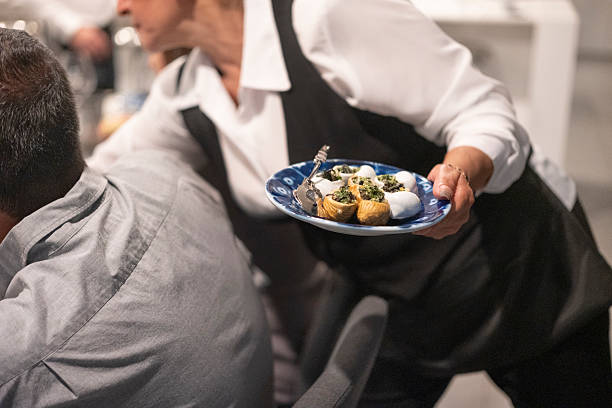 istock waiter at an elegant dinner serving Escargots de Bourgogne to guests 2231041579