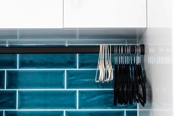 tidy matching hangers in laundry room with white cabinets black handles and dark teal tiled backsplash, organised home theme
