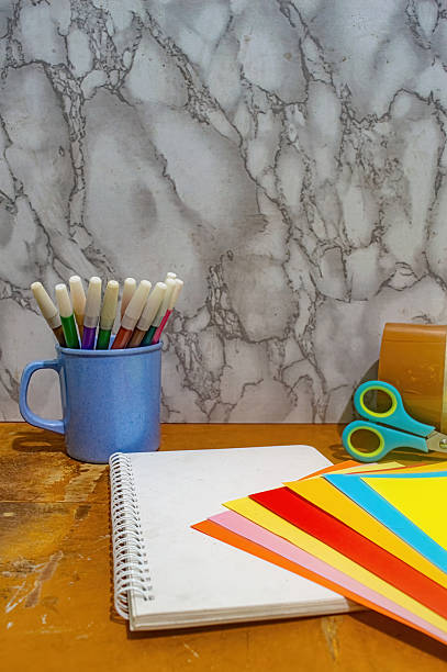 istock Close up of a notebook with colored paper, scissors, and markers in a blue cup. This image emphasizes creativity, education, and the tools used in arts and crafts projects 2231058836