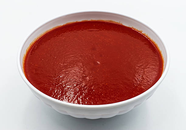istock A vibrant red and thick tomato-based sauce is presented in a simple white bowl, ready for culinary use. 2231060787