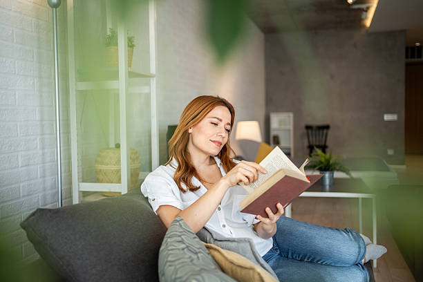 istock Woman relaxing on sofa reading a book at home 2231060855