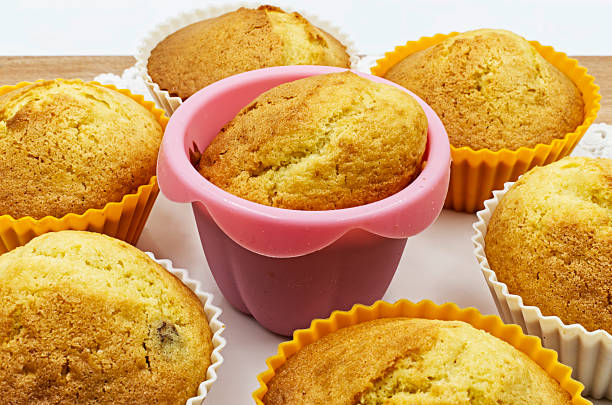 A delightful assortment of freshly baked golden muffins displayed in vibrant silicone and paper liners on a light surface, perfect for a sweet morning treat.