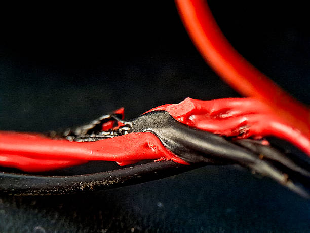 Entwined red and black electrical wires are depicted in sharp focus against a gradient dark background, highlighting texture and interplay of color in minimalist style.