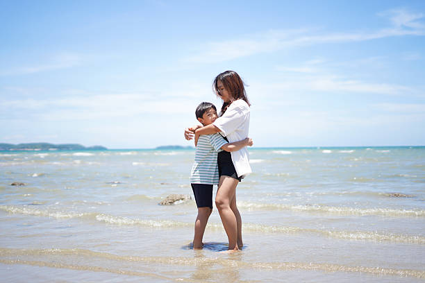 Mother and son hugging on the beach at the sea.