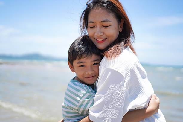 istock Mother and son happily hug each other on the beach. 2231066151
