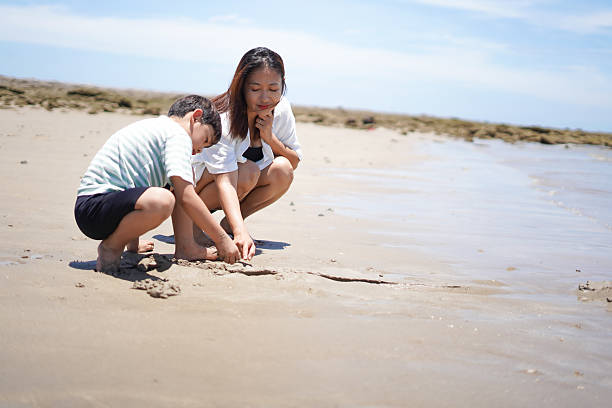istock Mother and son playing in the sand at the beach. 2231066357