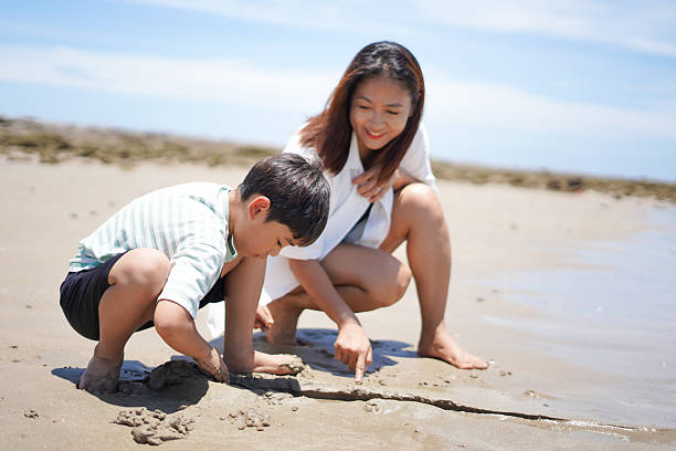 istock Mother and son playing in the sand at the beach. 2231066452