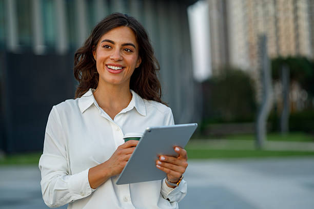 istock Young businesswoman enjoying coffee while using a digital tablet outside the office, embodying a modern and confident lifestyle 2231068529