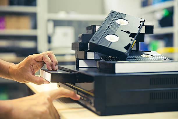 istock Close-up hand chooses and put or insert video cassette tape VHS on video record playback concept of retro style or vintage electric and electronic appliances multimedia player device old fashioned. 2231069125