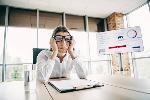 istock Tired woman stressed while working in a contemporary office with a chart presentation in the background 2231071792