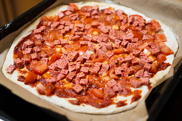Neapolitan-style homemade pizza: sausage cubes and fresh tomatoes before baking.