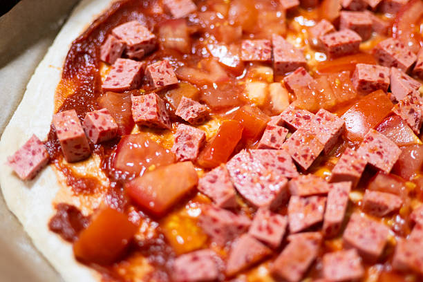 Neapolitan-style homemade pizza: sausage cubes and fresh tomatoes before baking.
