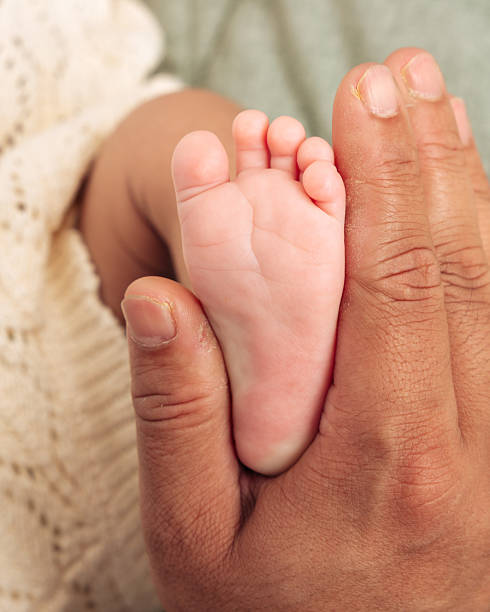 istock Parent Holding Babys Foot in Gentle Touch 2231073768