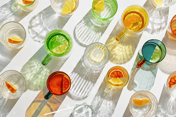 istock Vivid Glasses with cold detox water as summer still life pattern, shadow and sunlight refraction, closeup glass cups of infused fruit water, slises of lemon, orange, healthy summer drink 2231074239