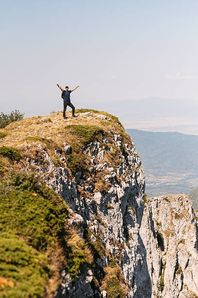 istock Hiker standing on mountain cliff with arms outstretched 2231074342