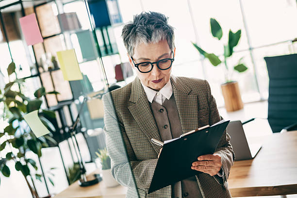 istock Elegant senior businesswoman analyses documents in modern office interior, showcasing professionalism and style in corporate environment 2231075355