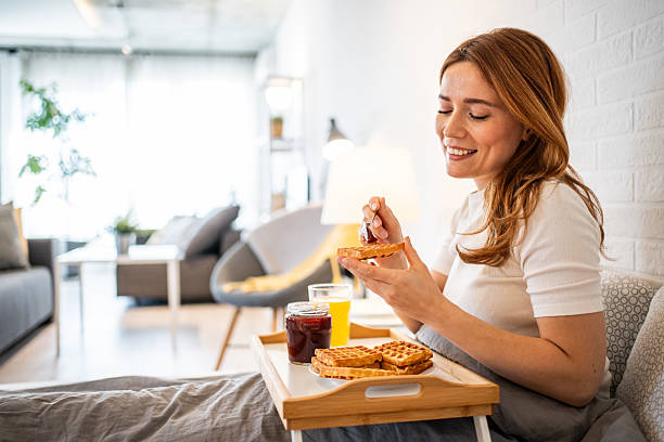 istock Young woman enjoying breakfast in bed with waffles and jam 2231075501