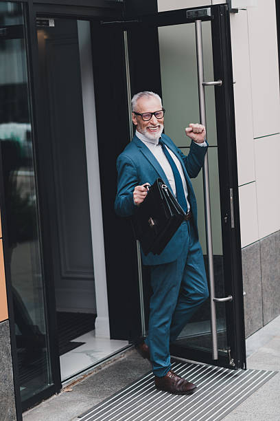 istock Confident senior businessman exiting office building with briefcase, symbolizing success and professionalism in real estate 2231075876