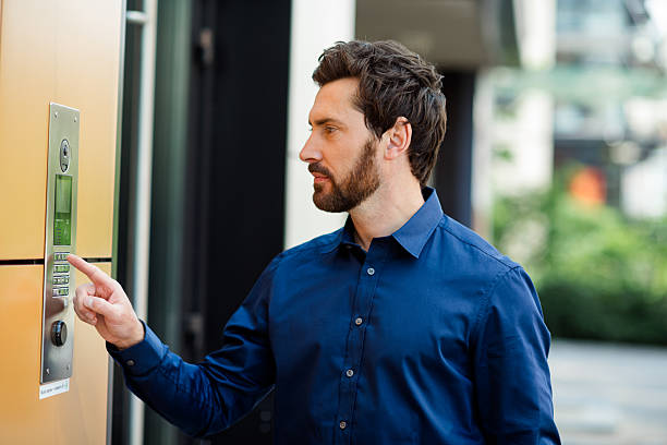 istock Handsome businessman interacting with building intercom in modern urban environment on a sunny day 2231077082