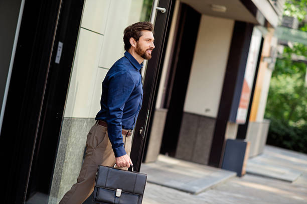 istock Confident young businessman walking outdoors with leather briefcase, dressed in elegant formalwear, urban background 2231077083