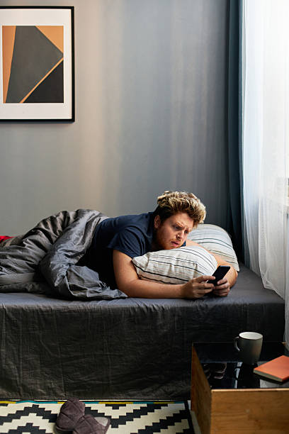 istock Man Waking up in Morning Looking at Smartphone Screen 2231077949