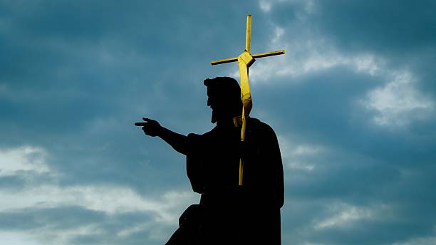 istock Silhouette of a statue with a cross against a dramatic sky. 2231078366