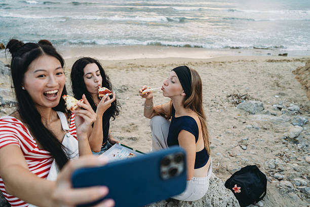 istock Young women taking selfie while eating pizza at the beach 2231079013